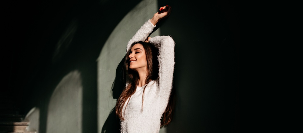 Young woman smiling confidently while standing in warm sunlight, showing healthy teeth and happiness – Dentist Southwest Ranches
