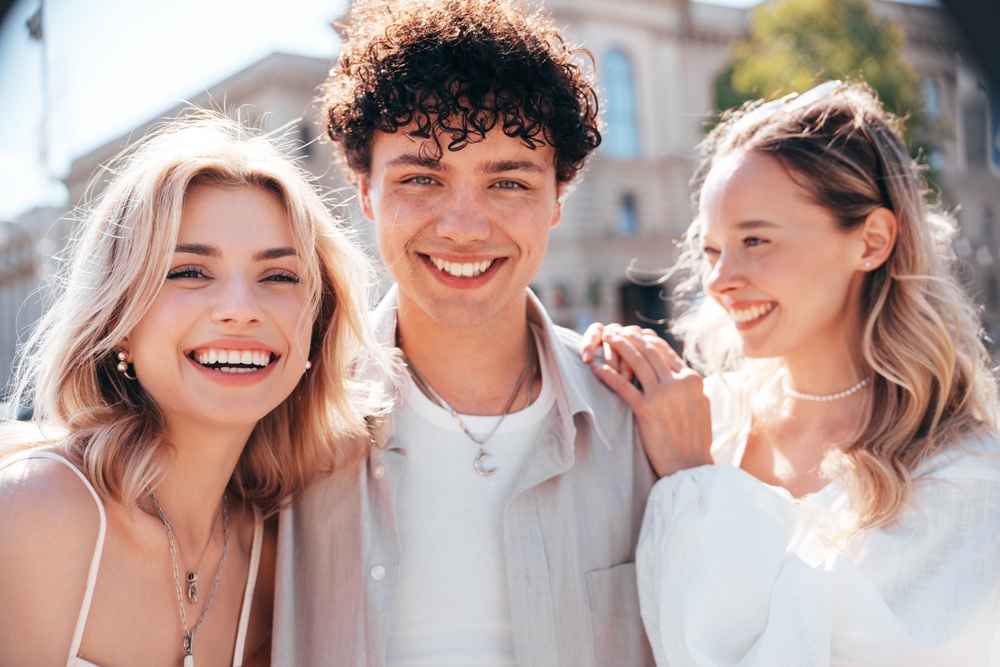 Group of young adults smiling happily outdoors on a bright day, showing their healthy teeth – Dentist Southwest Ranches